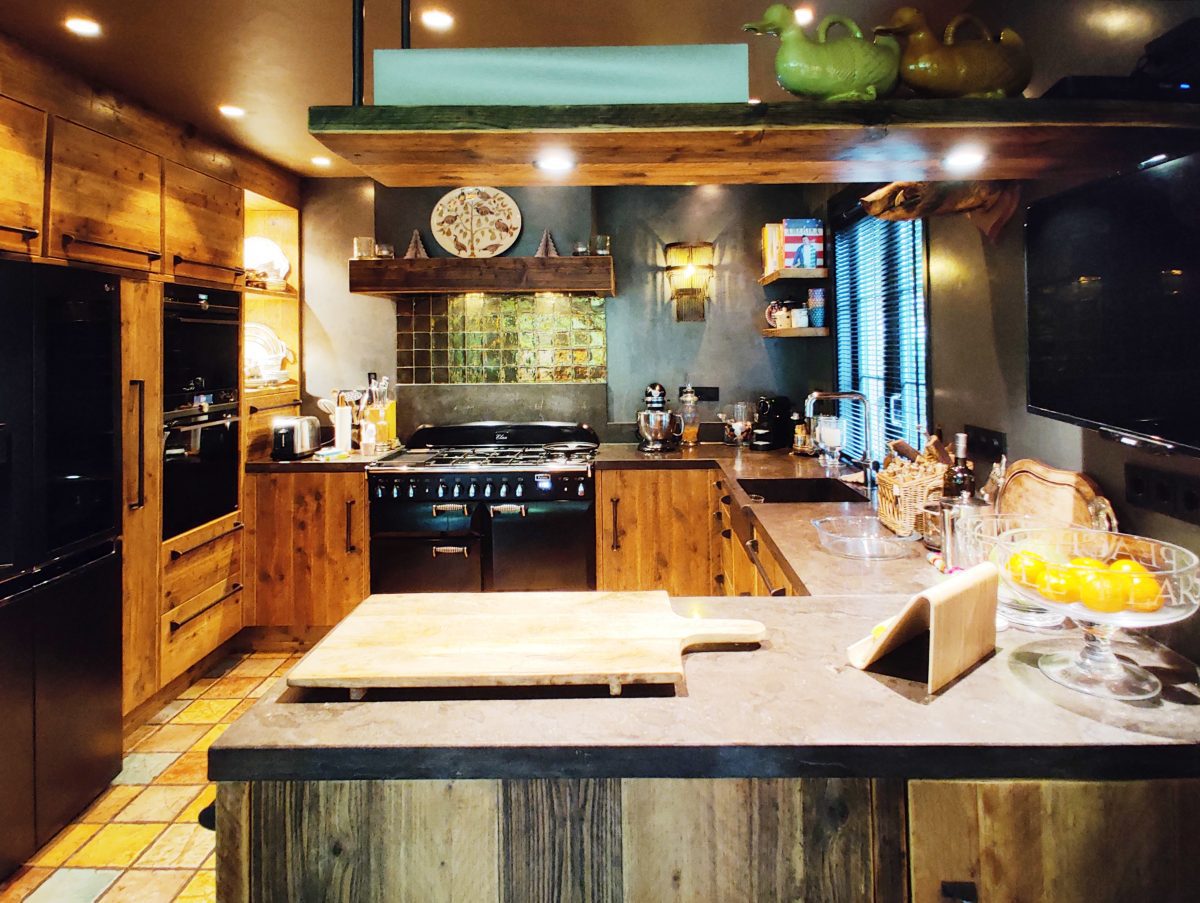 Een sfeervolle ronde keuken gemaakt van solide steigerhout met op maat gemaakte industriële grepen. Het aanrechtblad en de gootsteen zijn van hardsteen, oftewel natuursteen.